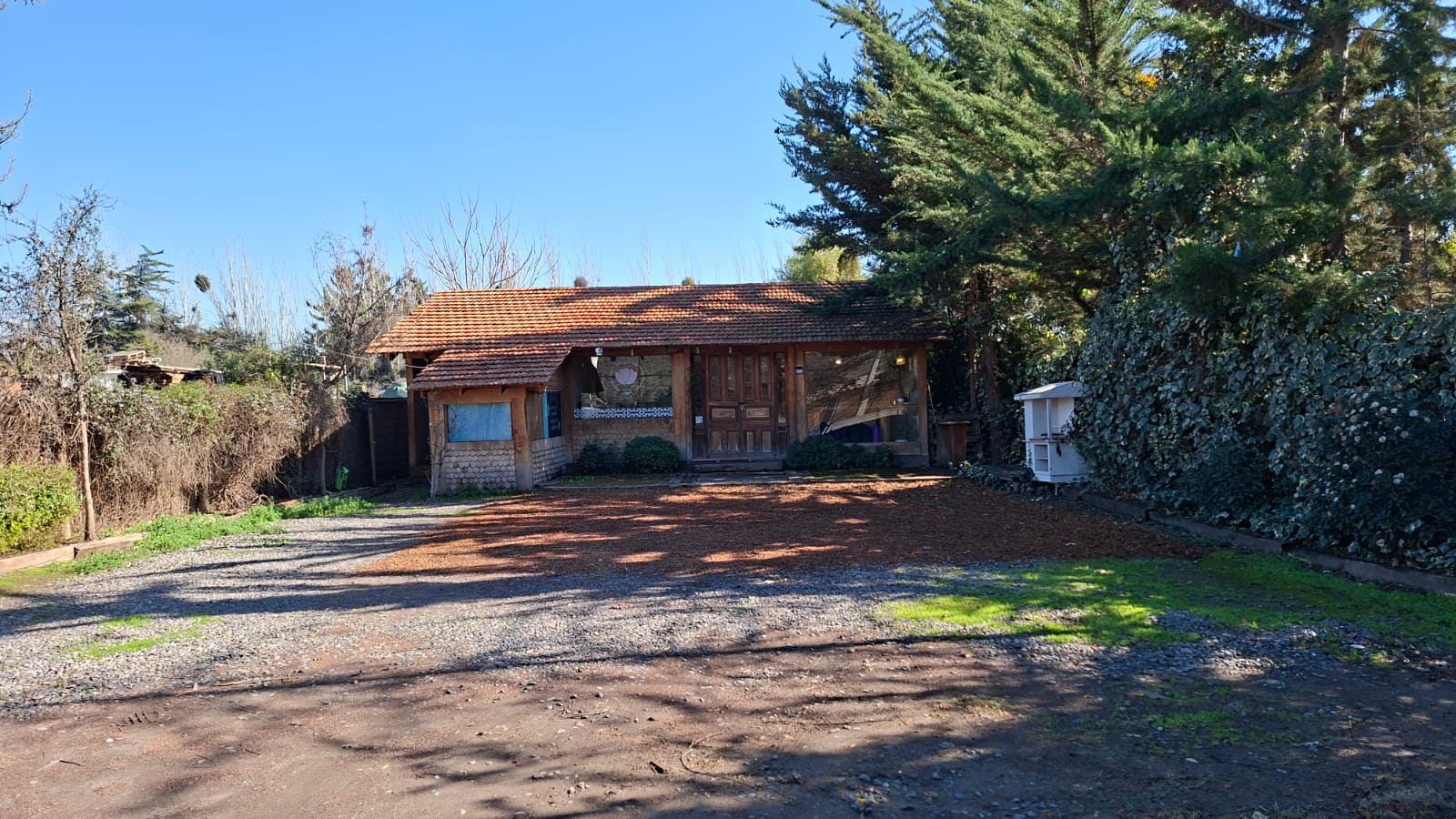 Fachada de Espacio Magnolia, casa con techo de tejas rodeada de árboles